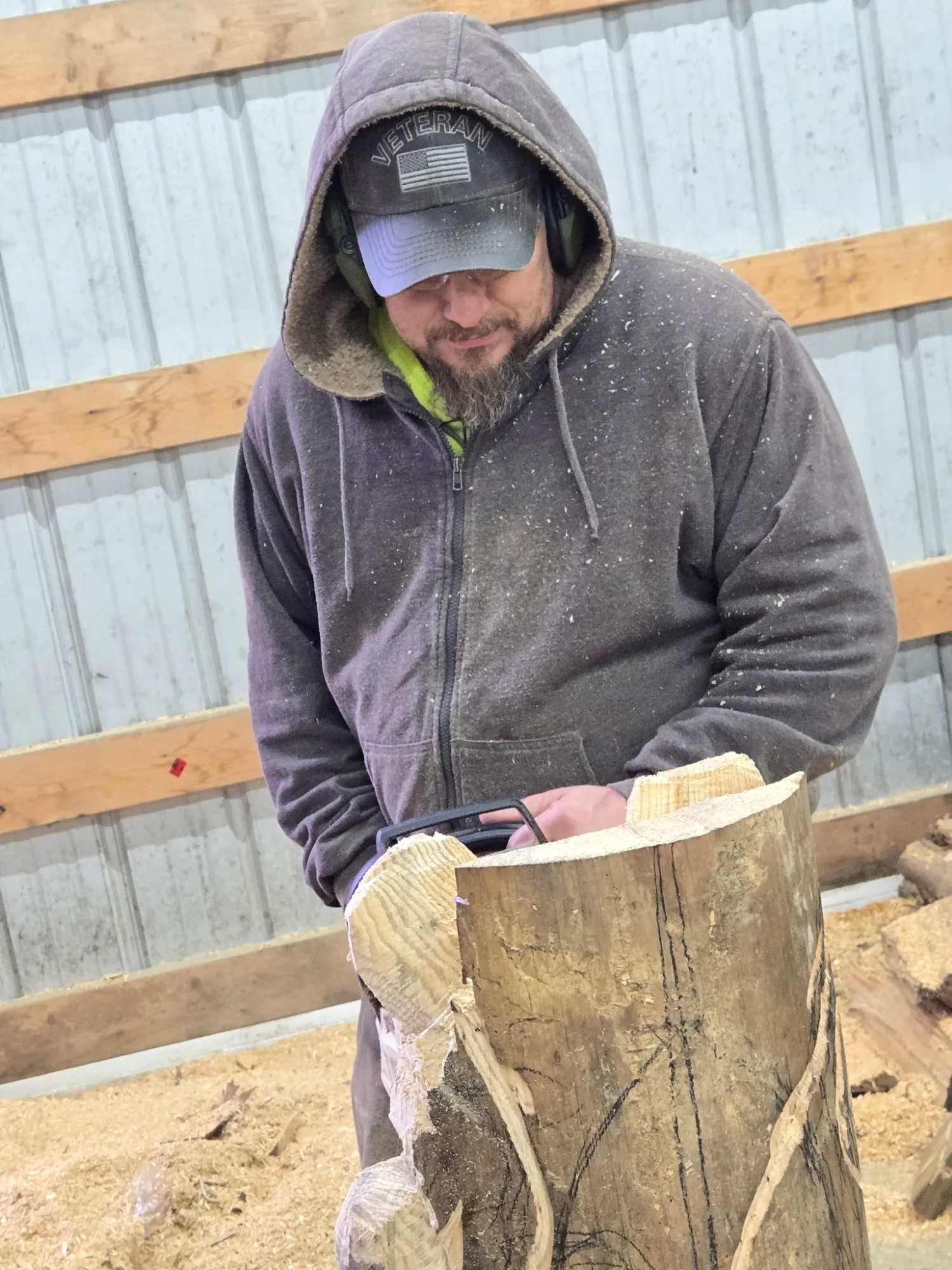 Gene in the workshop shaping a log with sawdust flying