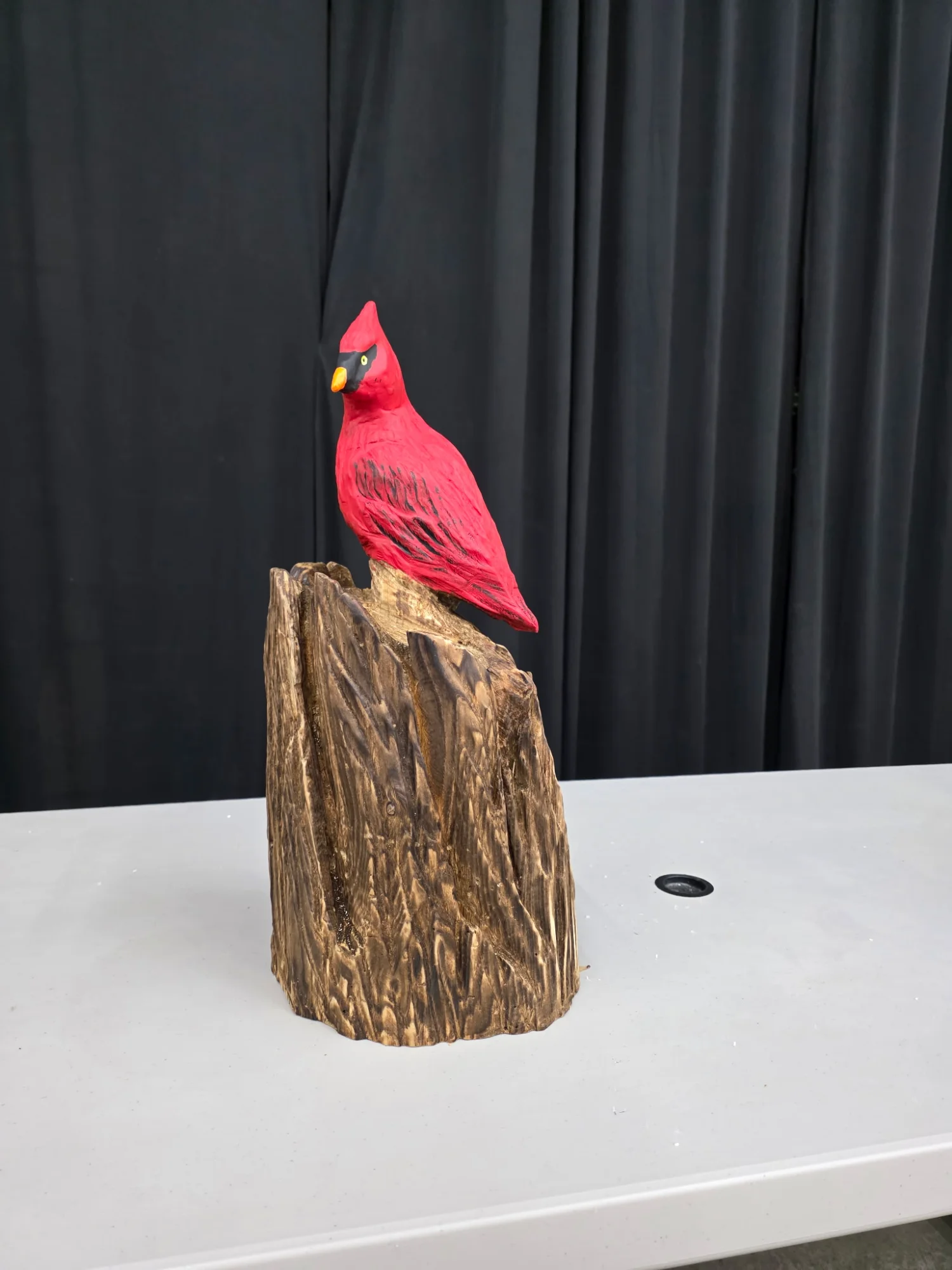 Bright red Cardinal chainsaw carving perched on a natural wood stump